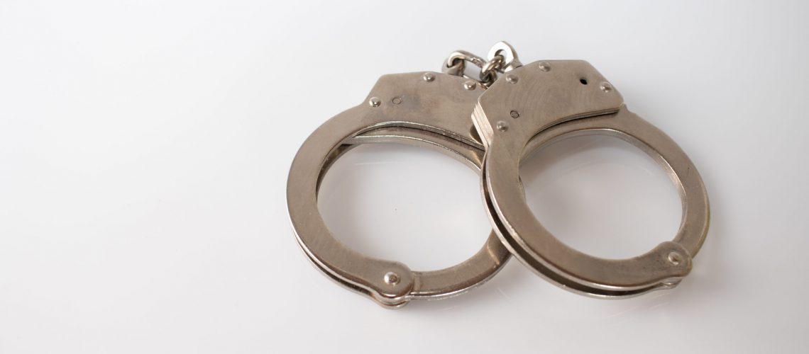 A high angle shot of metal handcuffs isolated on a white background